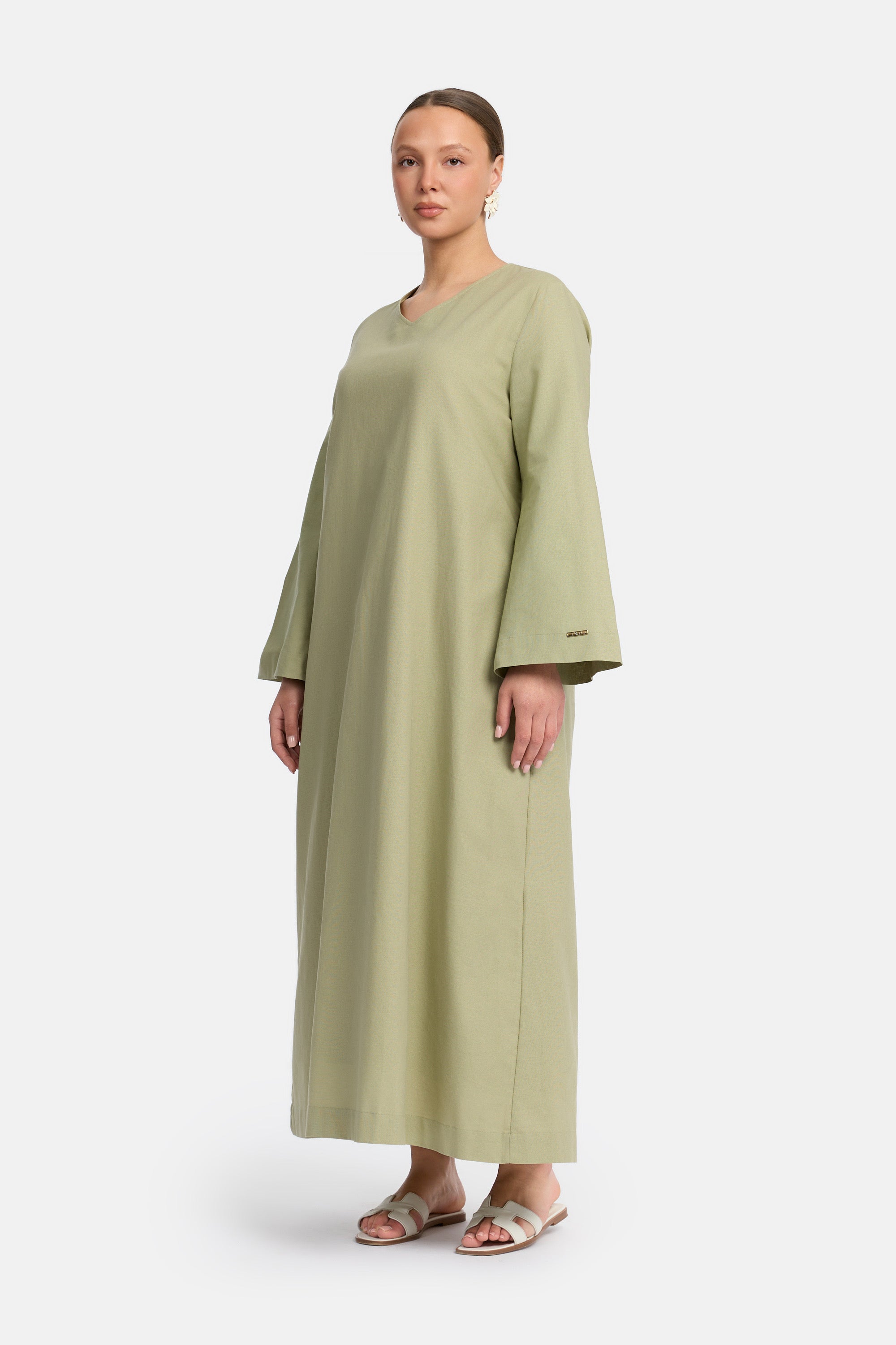 zij aanzicht van Model die draagt een modest linen loose dress van het merk enti in de kleur pastel green