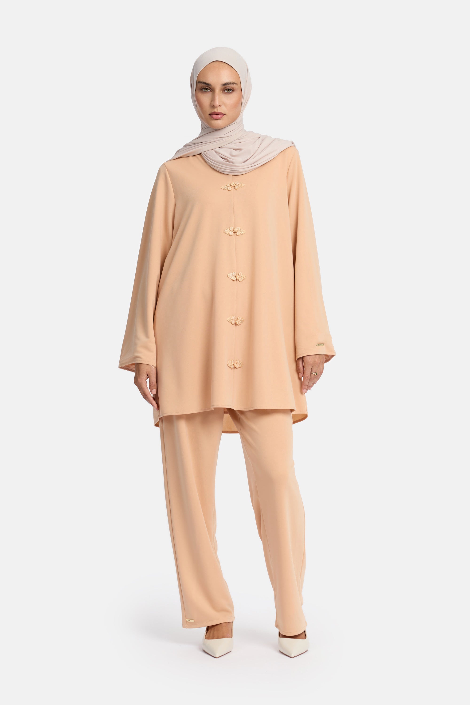 voor aanzicht van Model die draagt een modest kaftan set van het merk enti in de kleur pastel orange