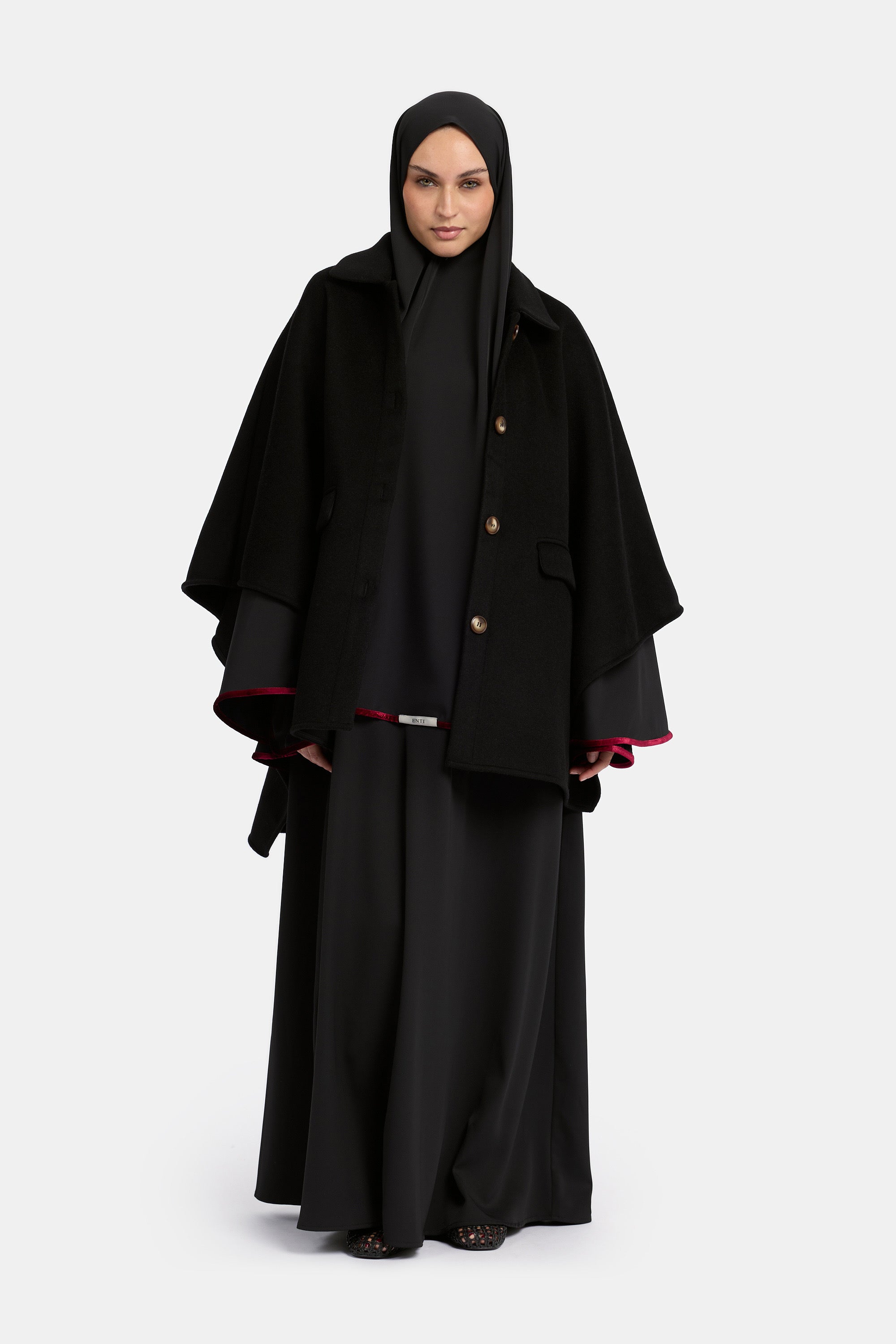 voor aanzicht van model die draagt de mastour velvet khimar en abaya set in de kleur zwart met de enti wool poncho.
