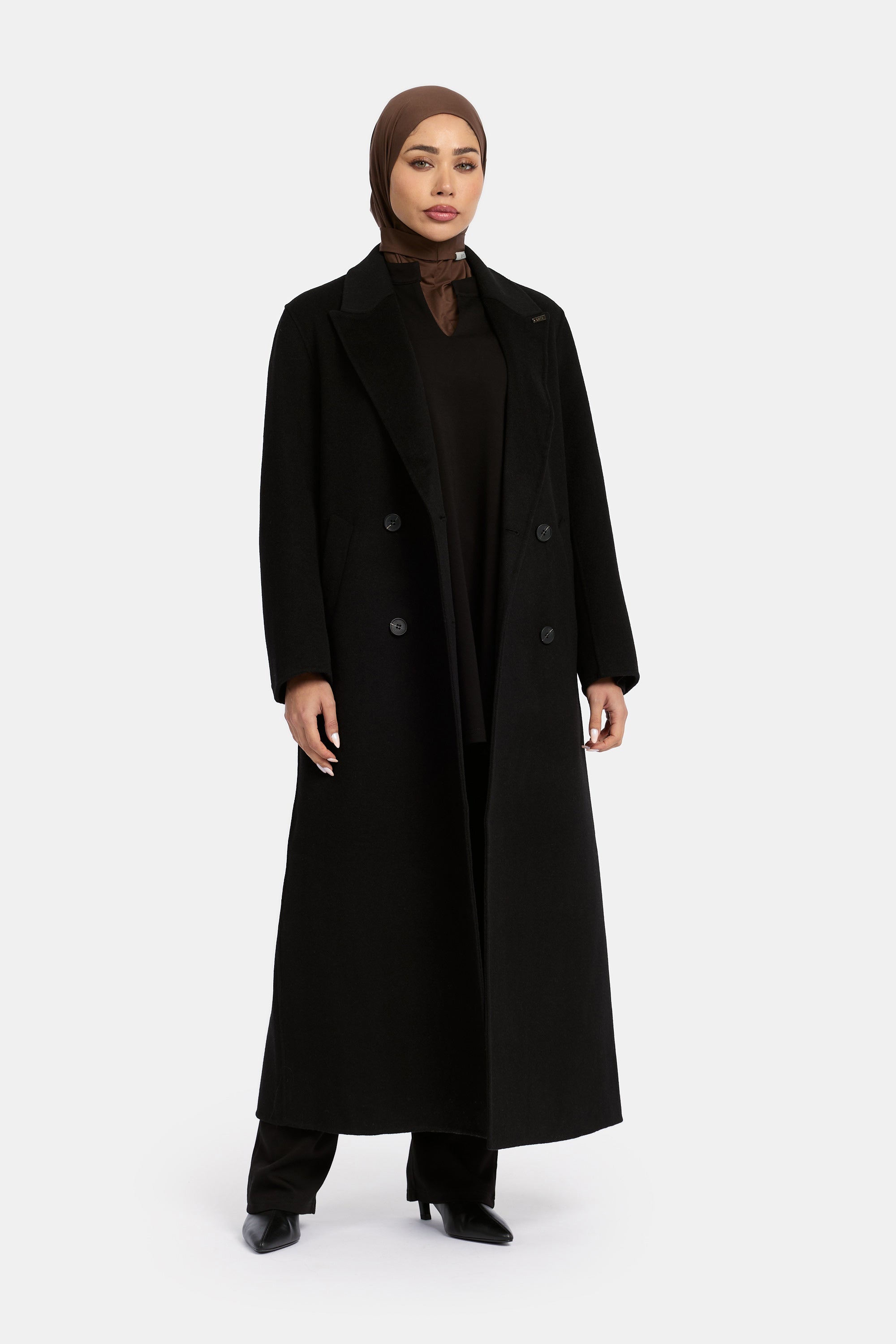 model draagt de wollen jas van het modest merk enti in de kleur zwart