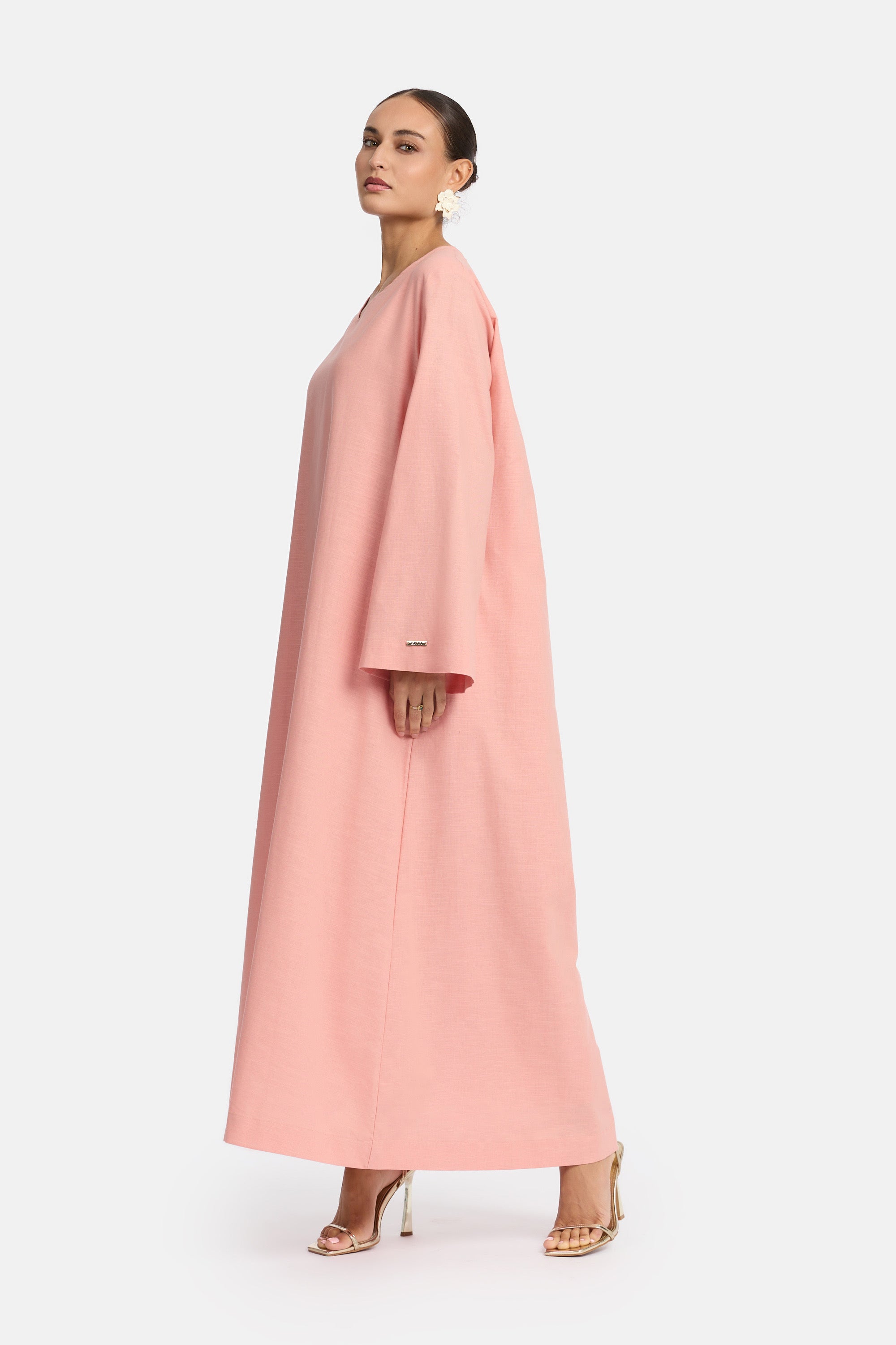 zij aanzicht van Model die draagt een modest linen loose dress van het merk enti in de kleur pastel pink