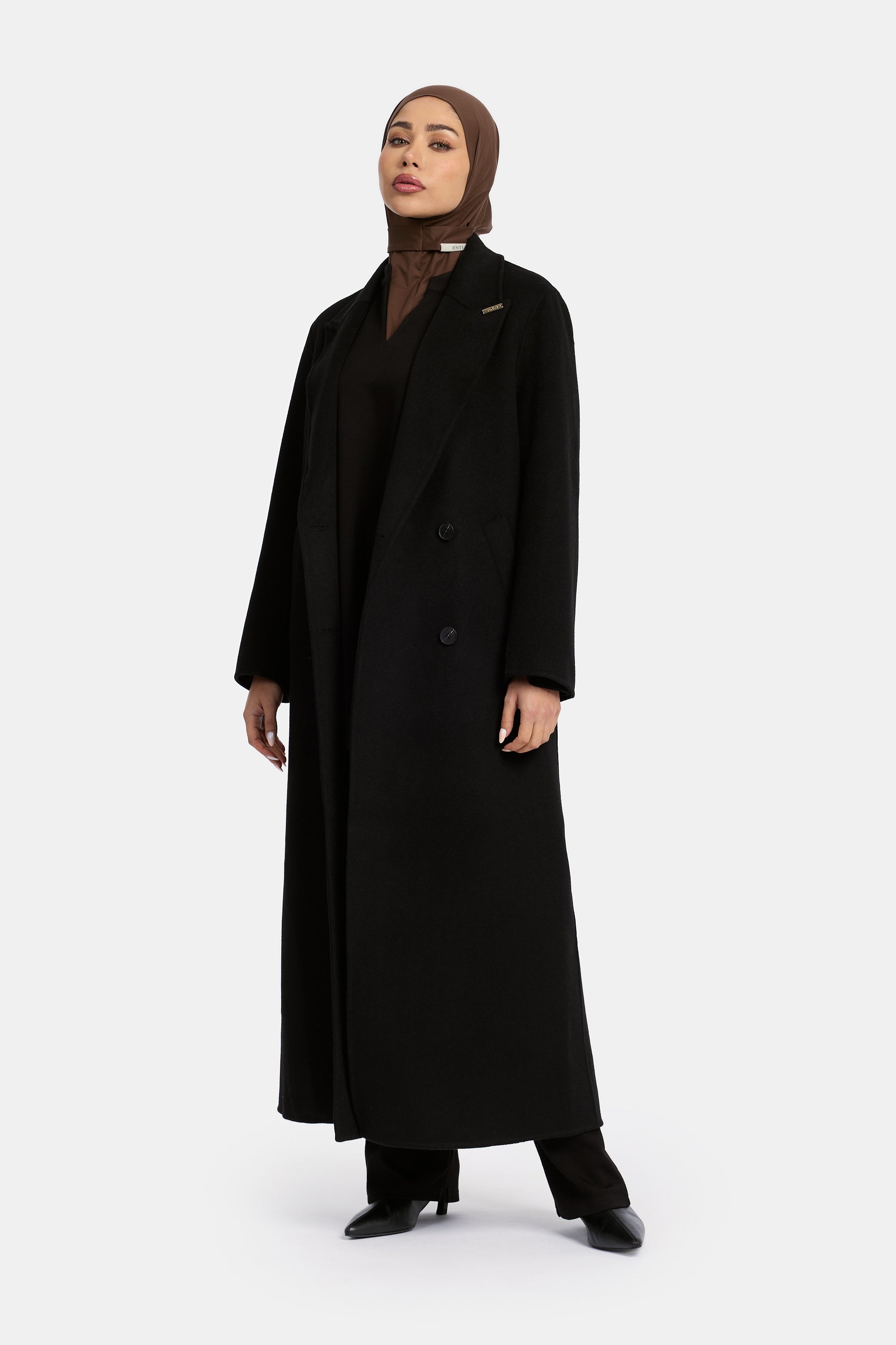 voor aanzicht model draagt de wollen jas van het modest merk enti in de kleur zwart