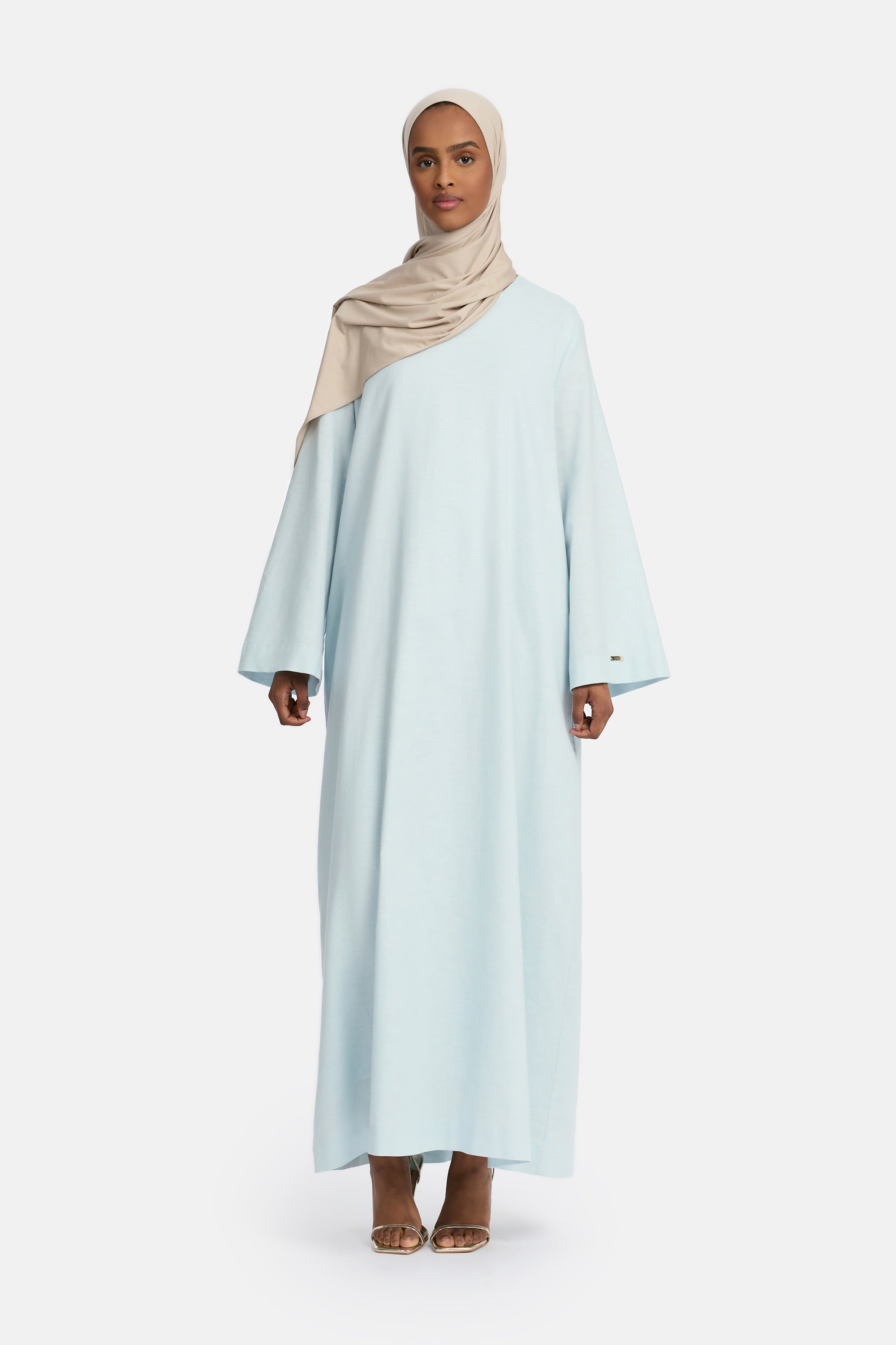 voor aanzicht van Model die draagt een modest linen loose dress van het merk enti in de kleur pastel blue