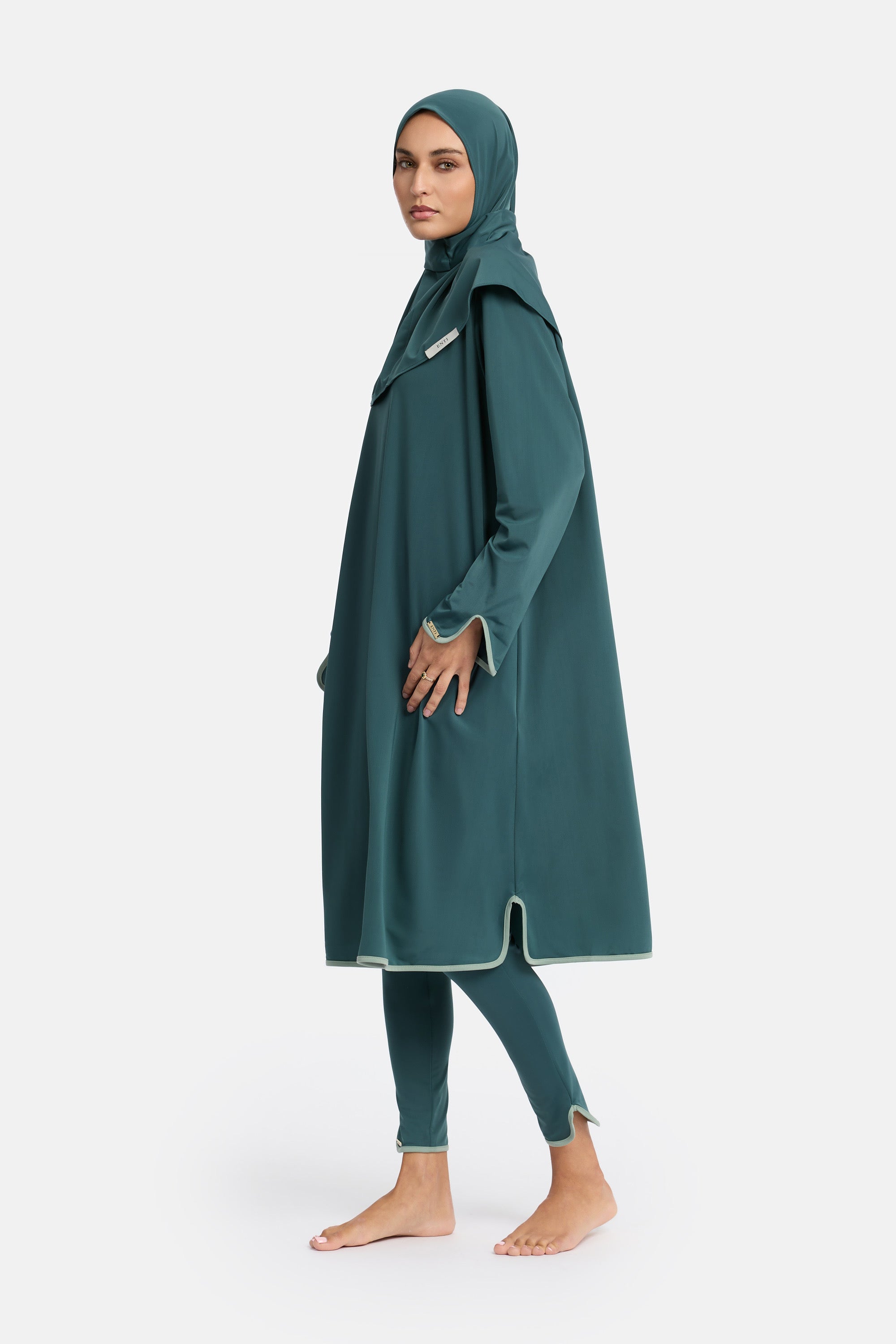zij aanzicht van model die de modest burkini van het merk enti draag met de zwem jurk en instant swim hijab in de kleur minty green