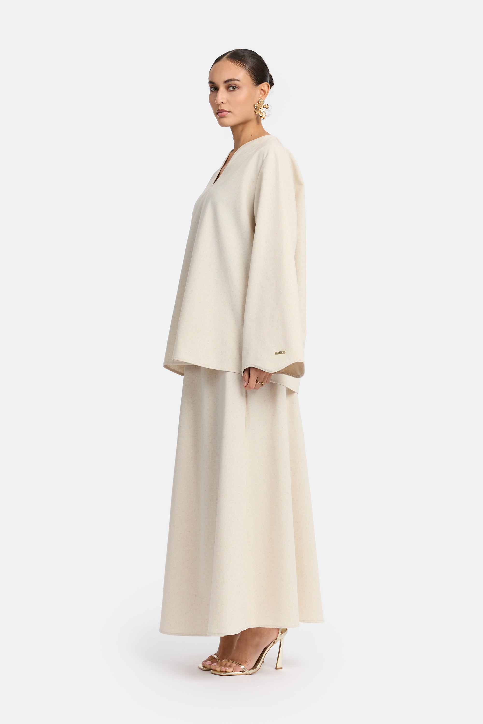 zij aanzicht van Model die draagt een modest linen skirt set van het merk enti in de kleur Soft beige