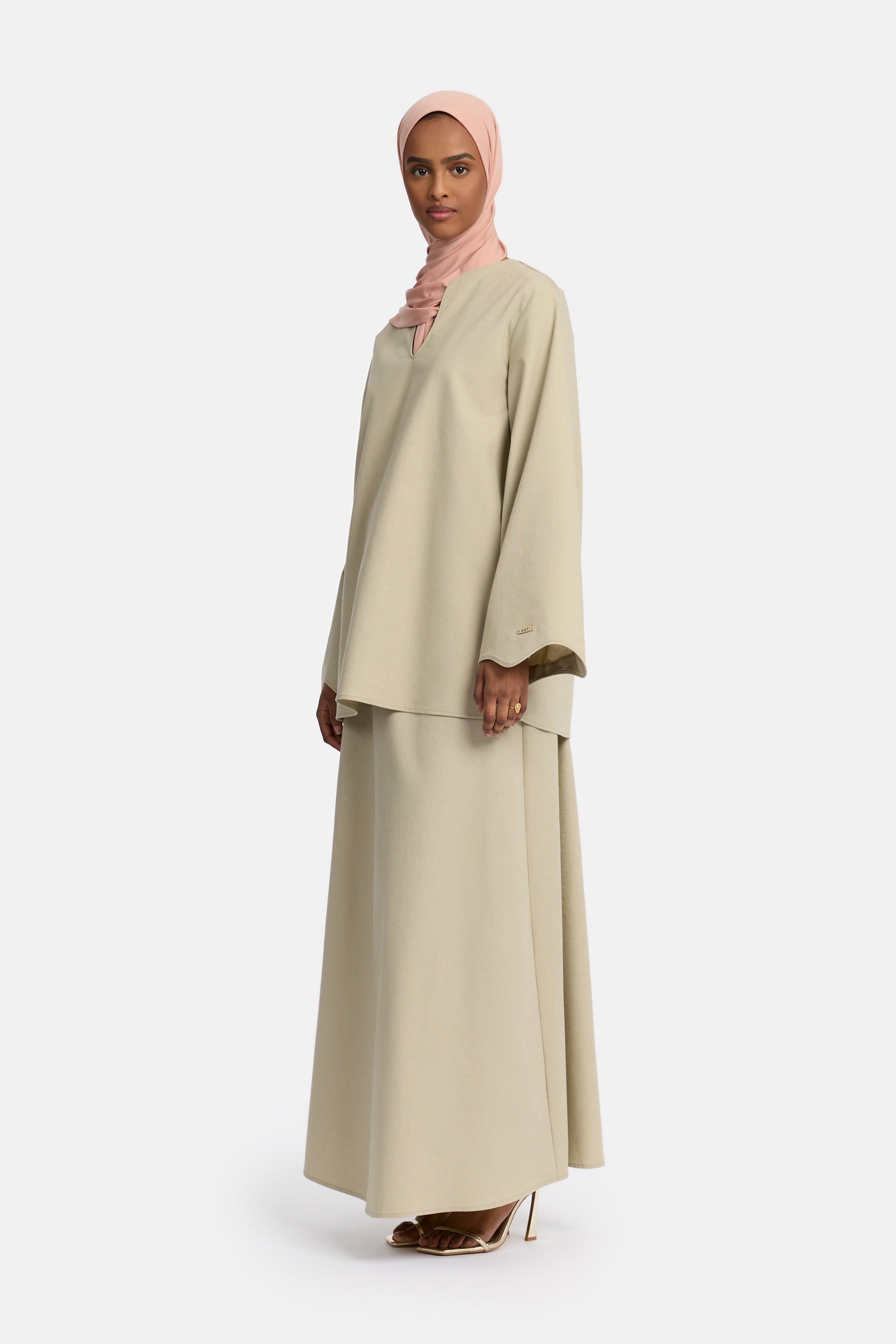 zij aanzicht van Model die draagt een modest linen skirt set van het merk enti in de kleur Light sage