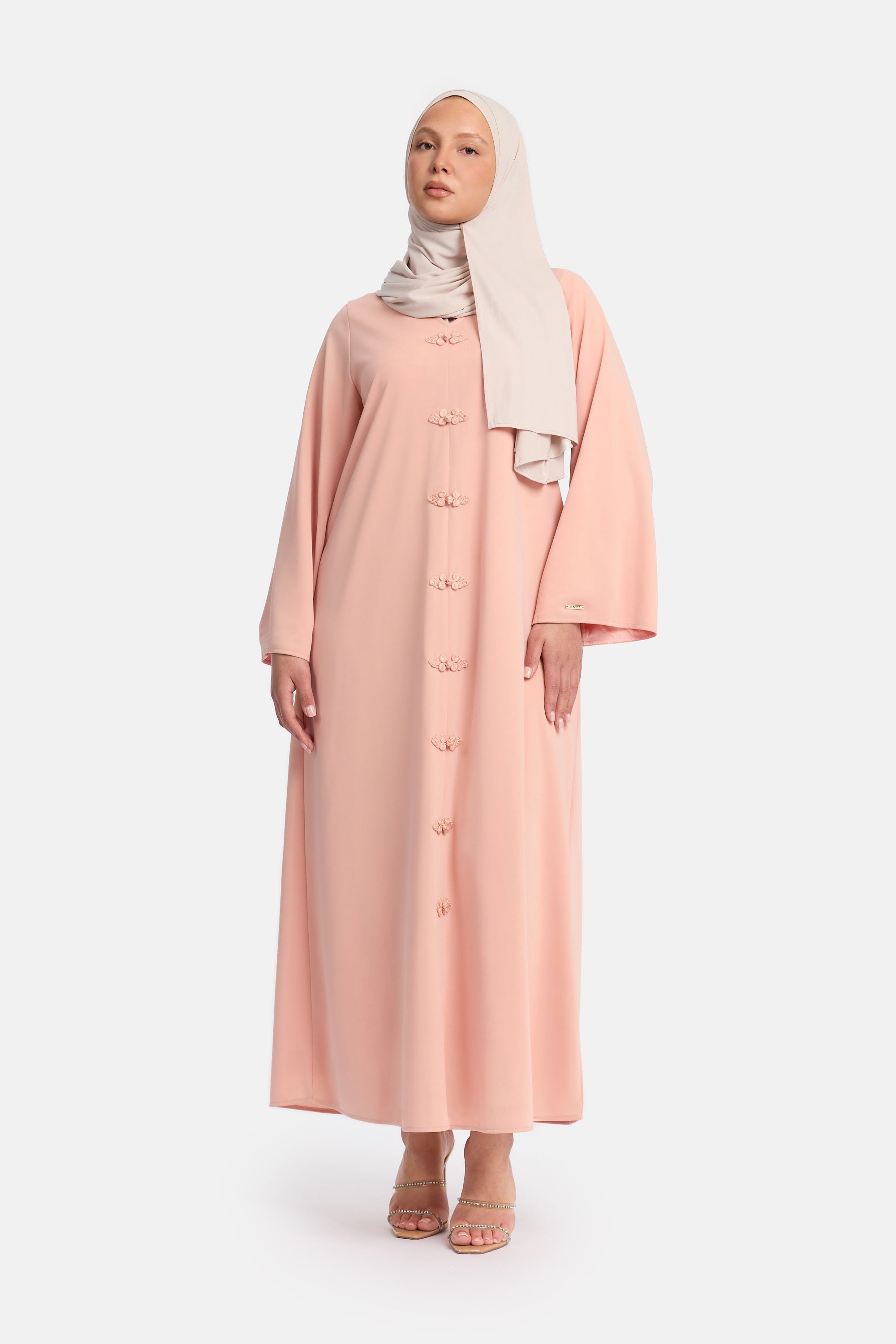 voor aanzicht van Model die draagt een modest kaftan dress van het merk enti in de kleur pastel roze  