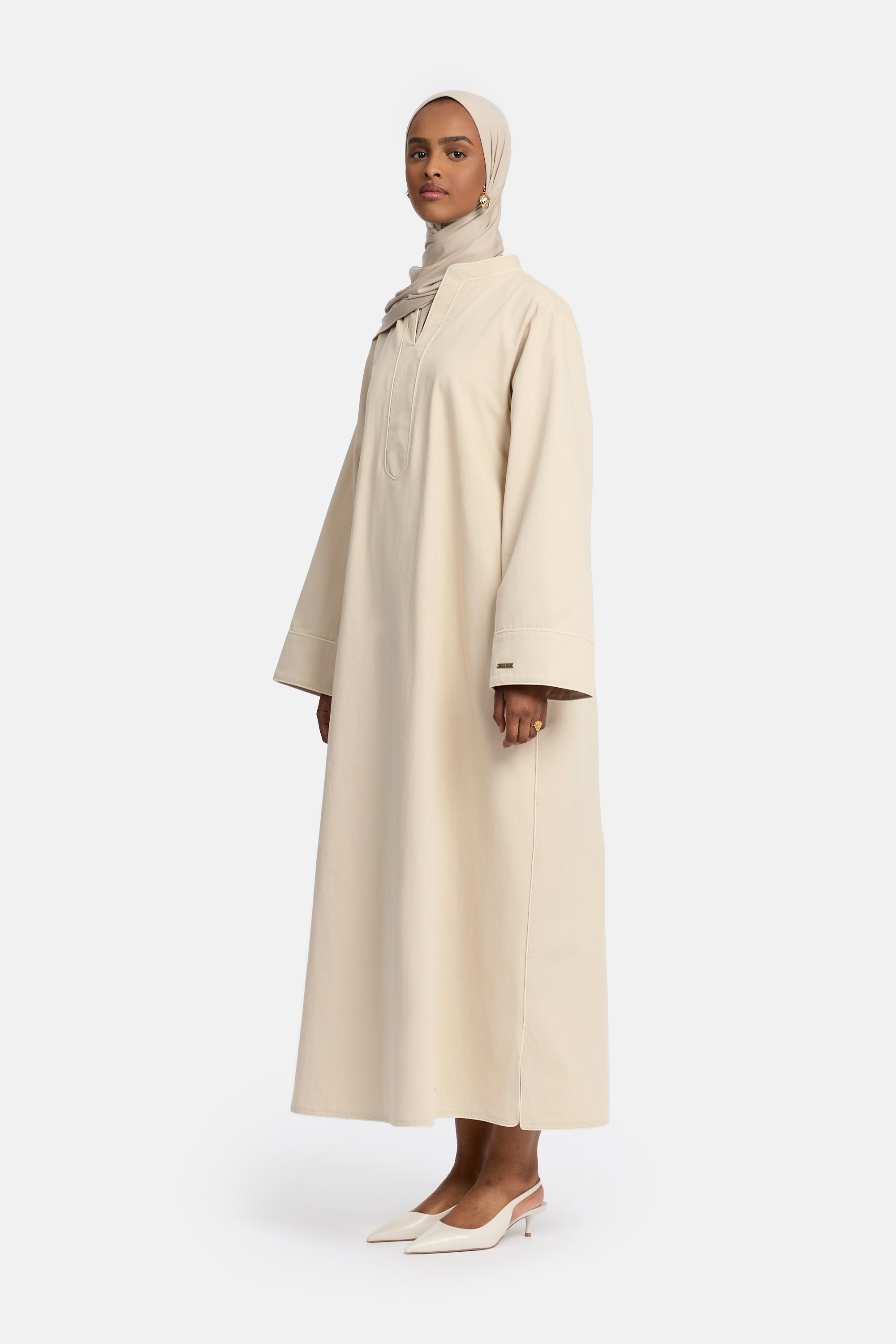 zij aanzicht van Model die draagt een modest cotton dress van het merk enti in de kleur soft beige