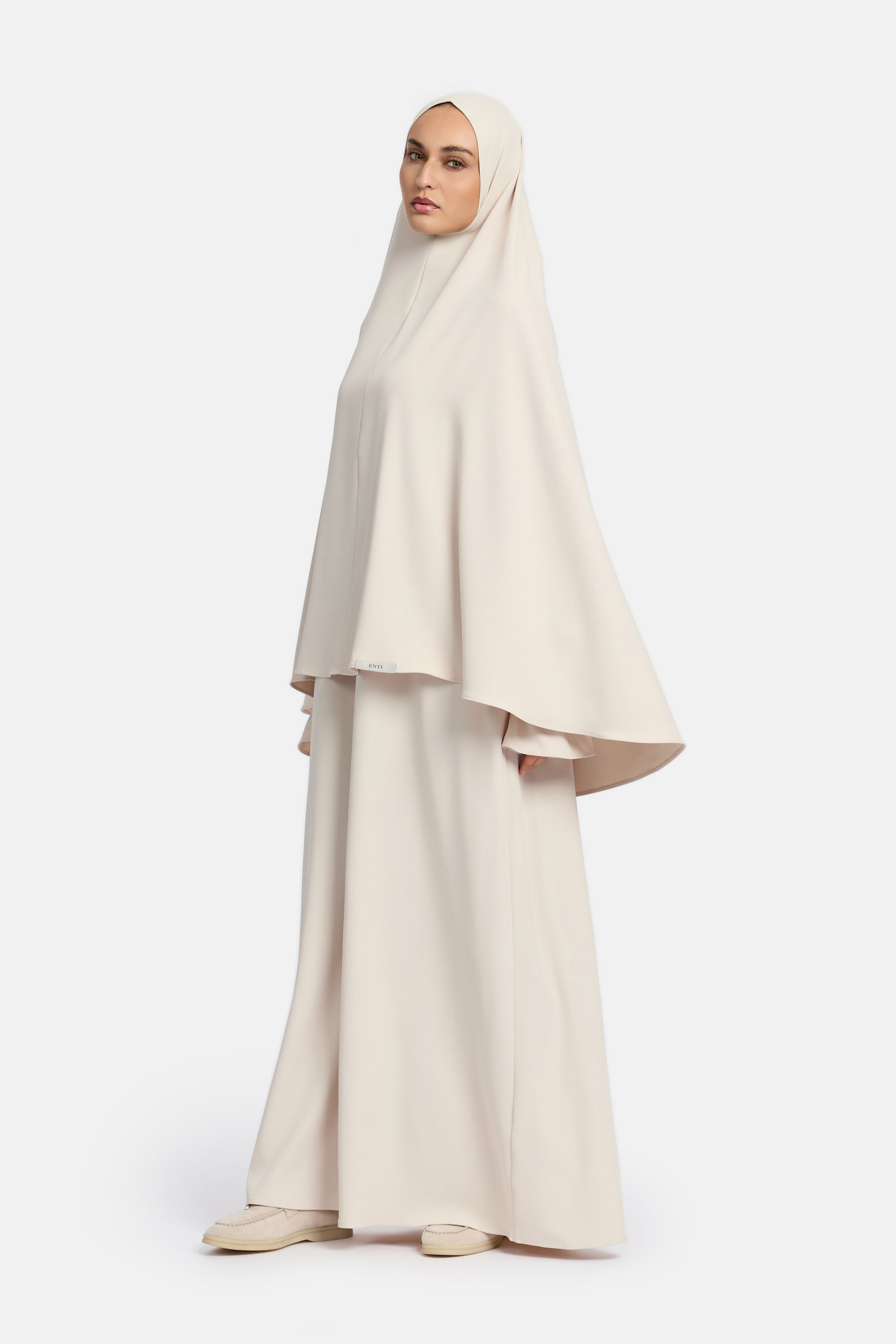 zij aanzicht van model die mastour set abaya en khimaar draagt van het merk ENTI in de kleur beige