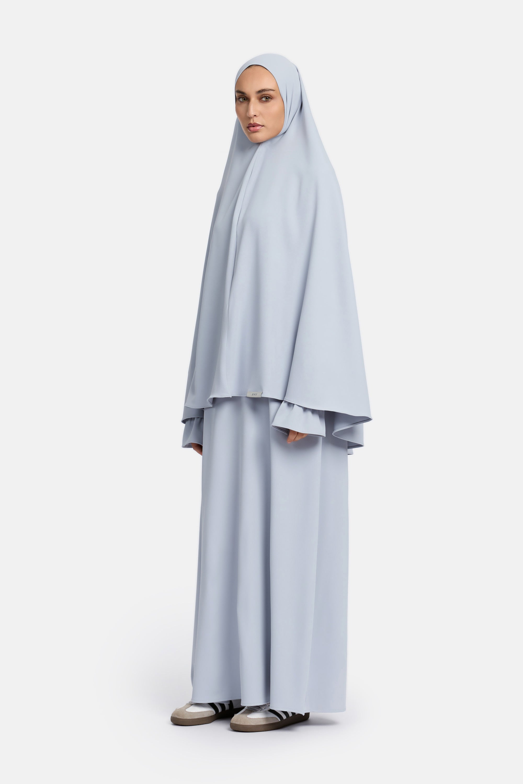 Zij aanzicht van model die mastour set abaya en khimaar draagt van het merk ENTI in de kleur blauw