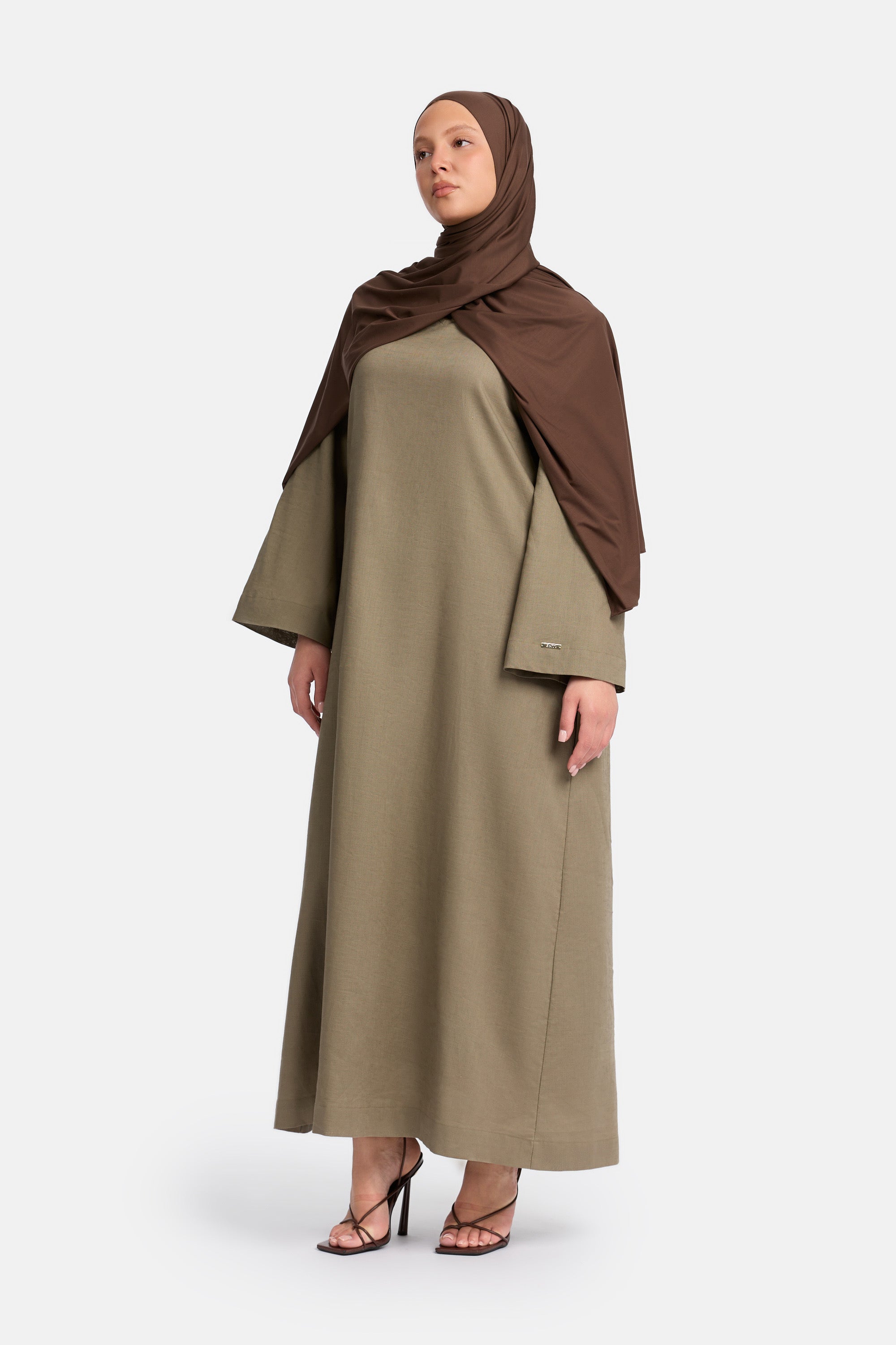 zij aanzicht van Model die draagt een modest linen loose dress van het merk enti in de kleur Ash brown